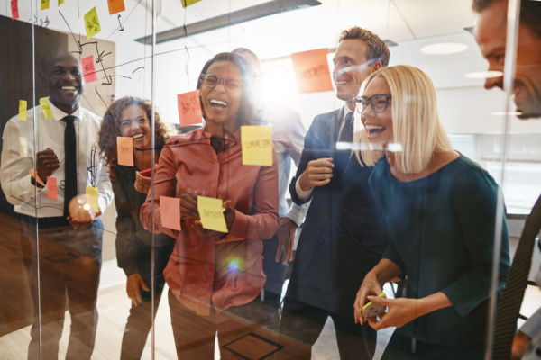 Laughing group of diverse businesspeople having a brainstorming session together with sticky notes in an office